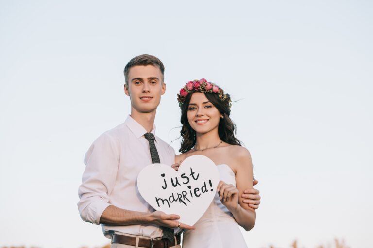 happy young wedding couple holding heart with just married inscription and smiling at camera